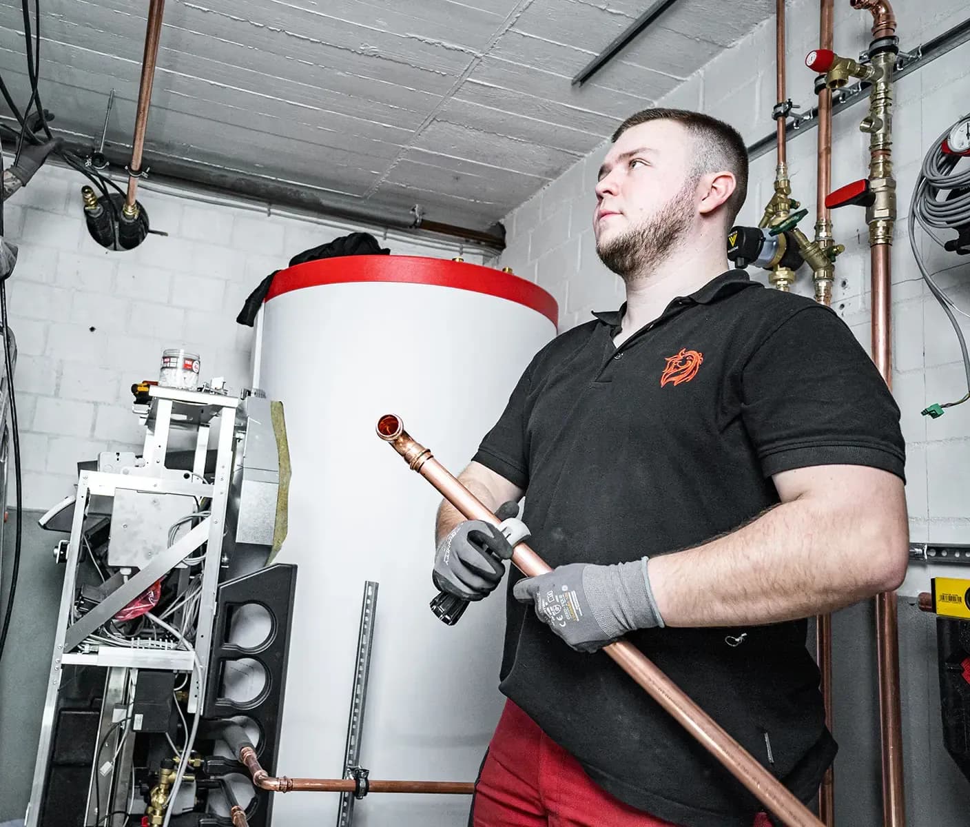 Rote Löwen Monteur mit Kupferrohren im Heizungskeller bei der Installation
