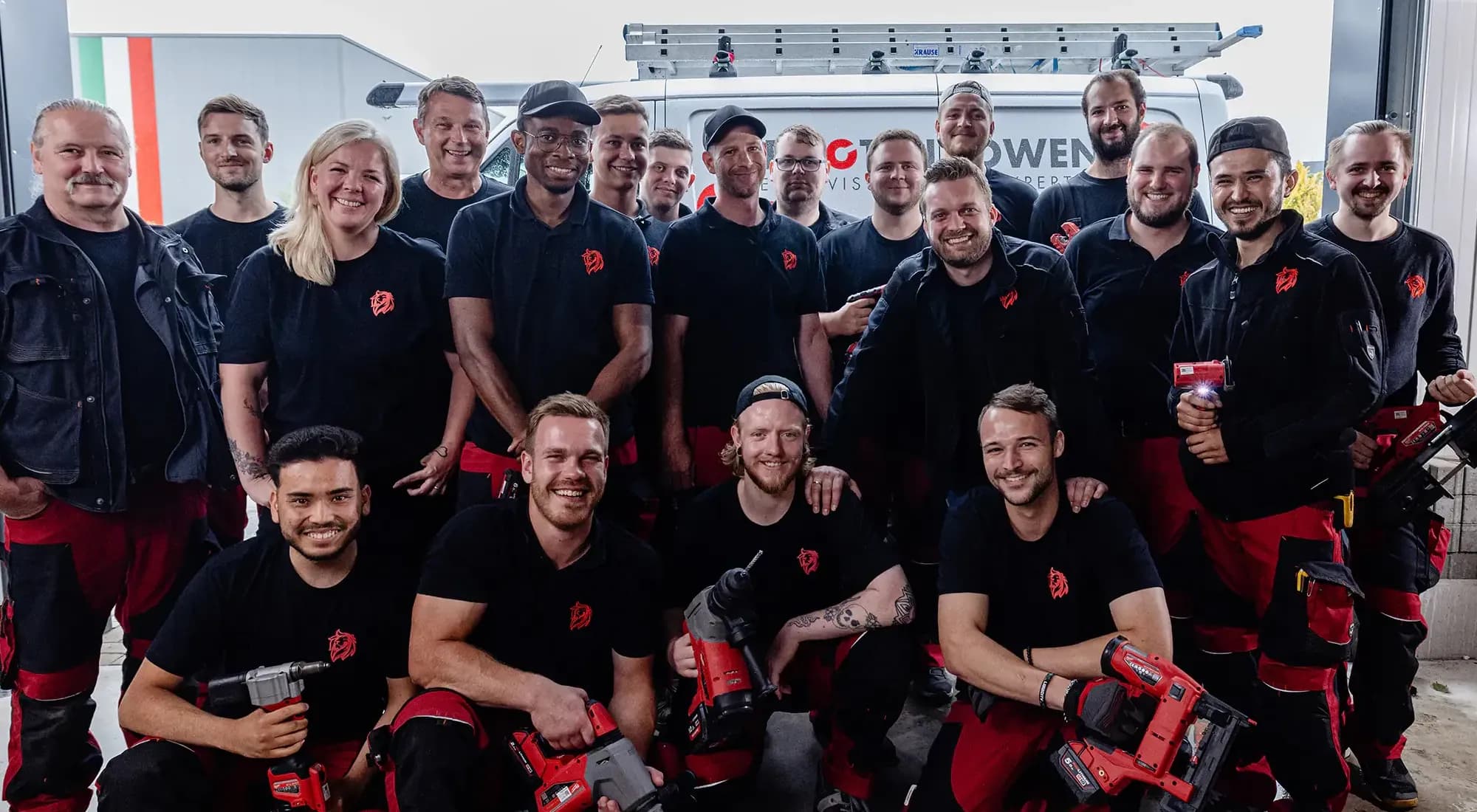 Die Roten Löwen Teamfoto - alle Mitarbeiter vor dem Firmenfahrzeug