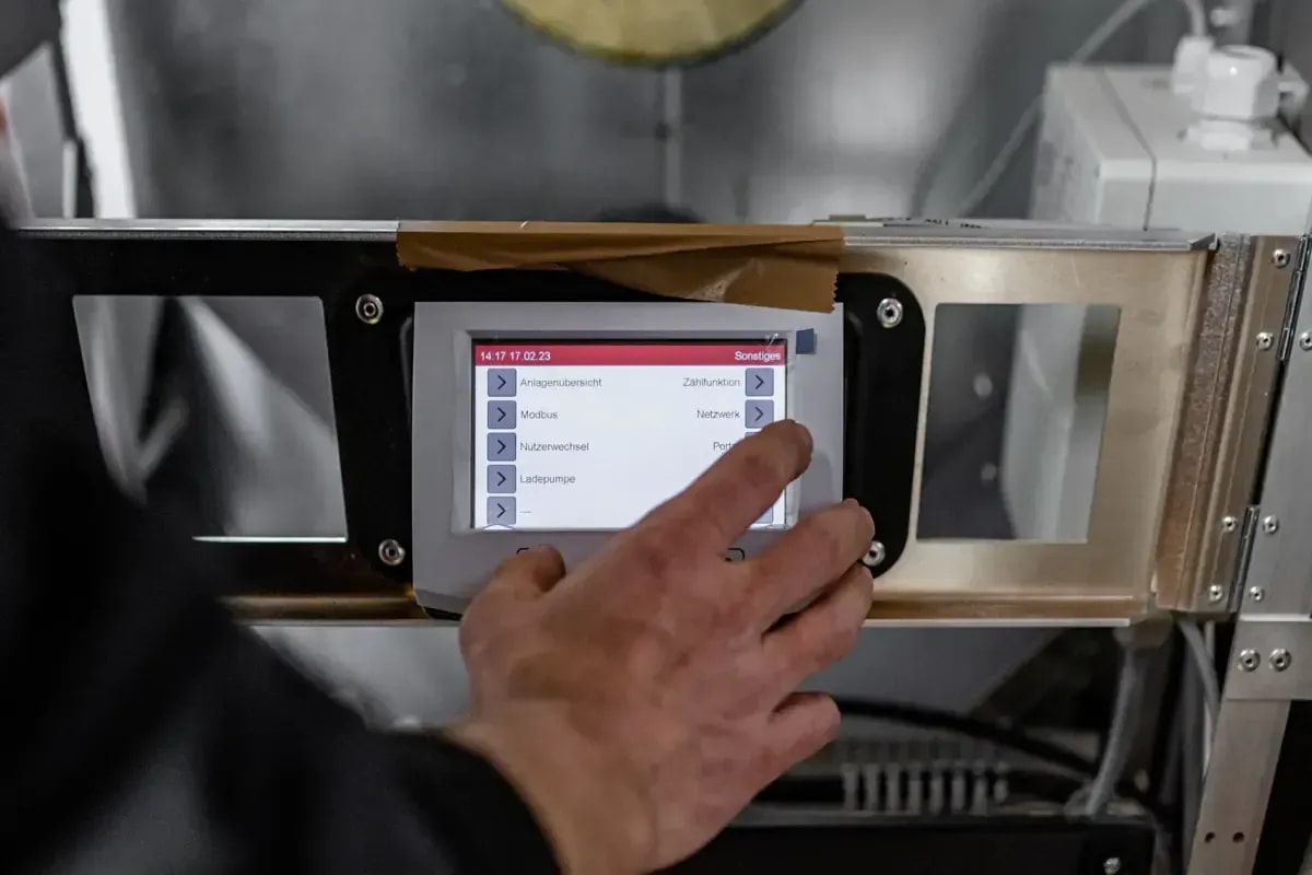 Techniker bedient Touchdisplay einer modernen Heizungssteuerung bei der Wartung