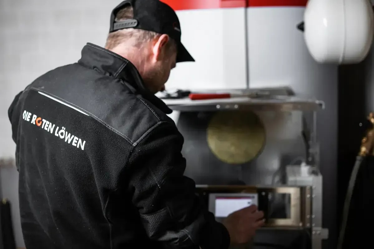 Techniker der Roten Löwen wartet moderne Heizung und prüft die Steuerung beim Kundendienst