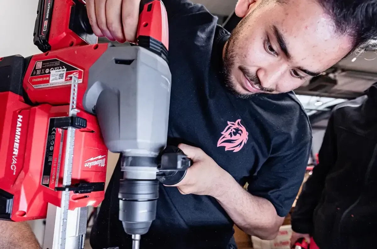 Monteur bohrt mit Milwaukee Akku-Bohrhammer bei Heizungsinstallation im Fachbetrieb