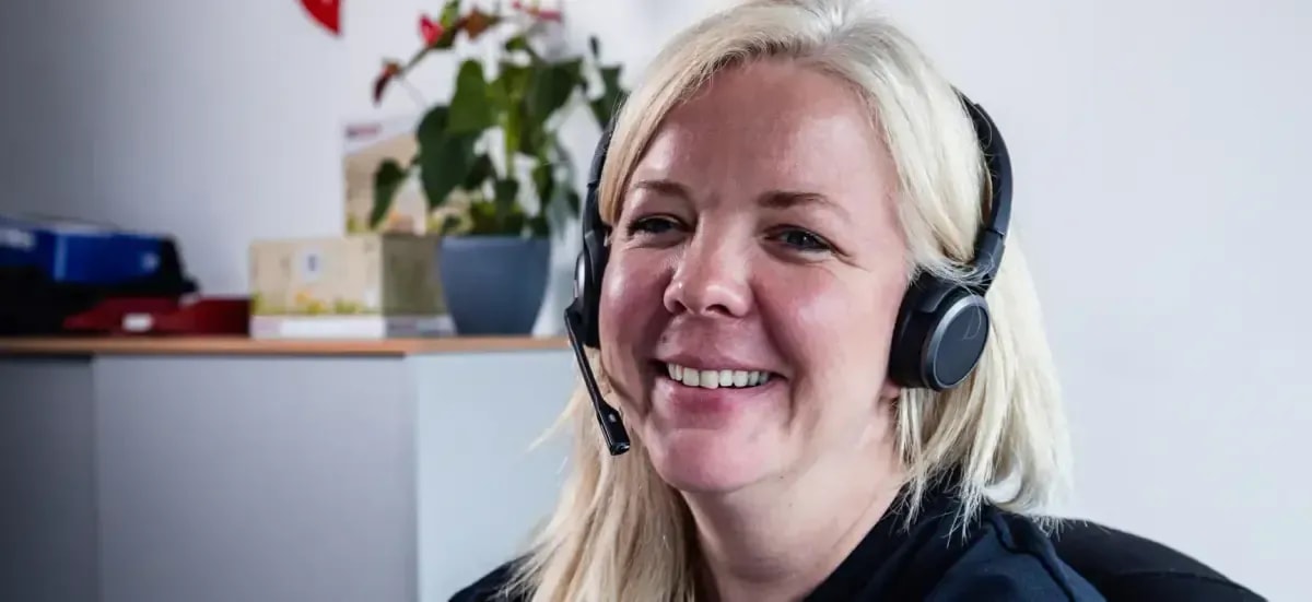 Freundliche Kundenservice-Mitarbeiterin mit Headset berät zu Heizung und Wartung