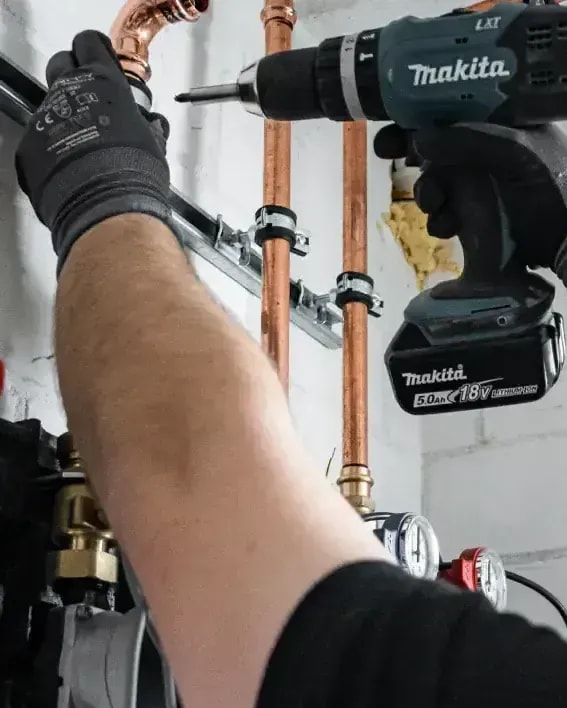 Monteur montiert Kupferrohre einer Heizung mit Akkuschrauber bei der Installation