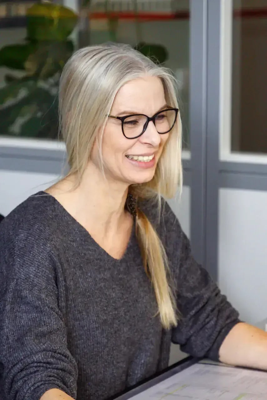 Lächelnde Mitarbeiterin mit Brille berät im Büro zu Heizung und Service